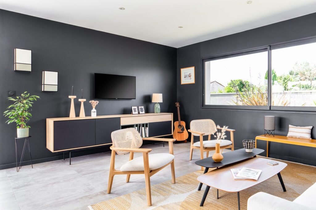 Salon d'une maison contemporaine à Rouffiac-Tolosan, murs anthracite, buffet en bois et fauteuils en cannage
