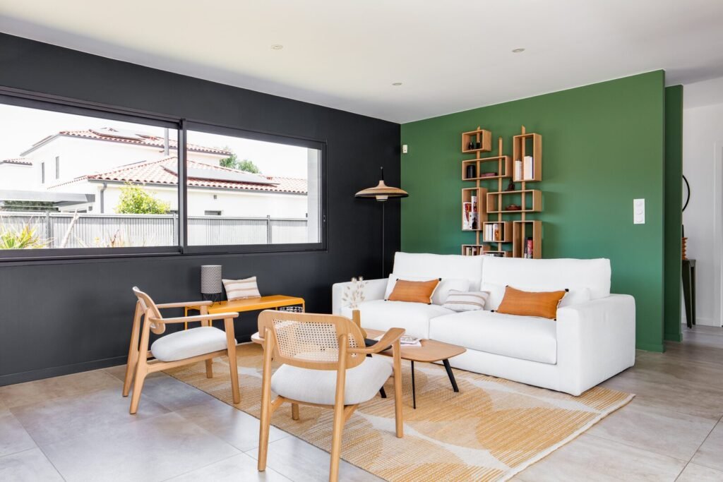 Canapé blanc et mur d'accent vert profond avec étagères en bois dans le salon